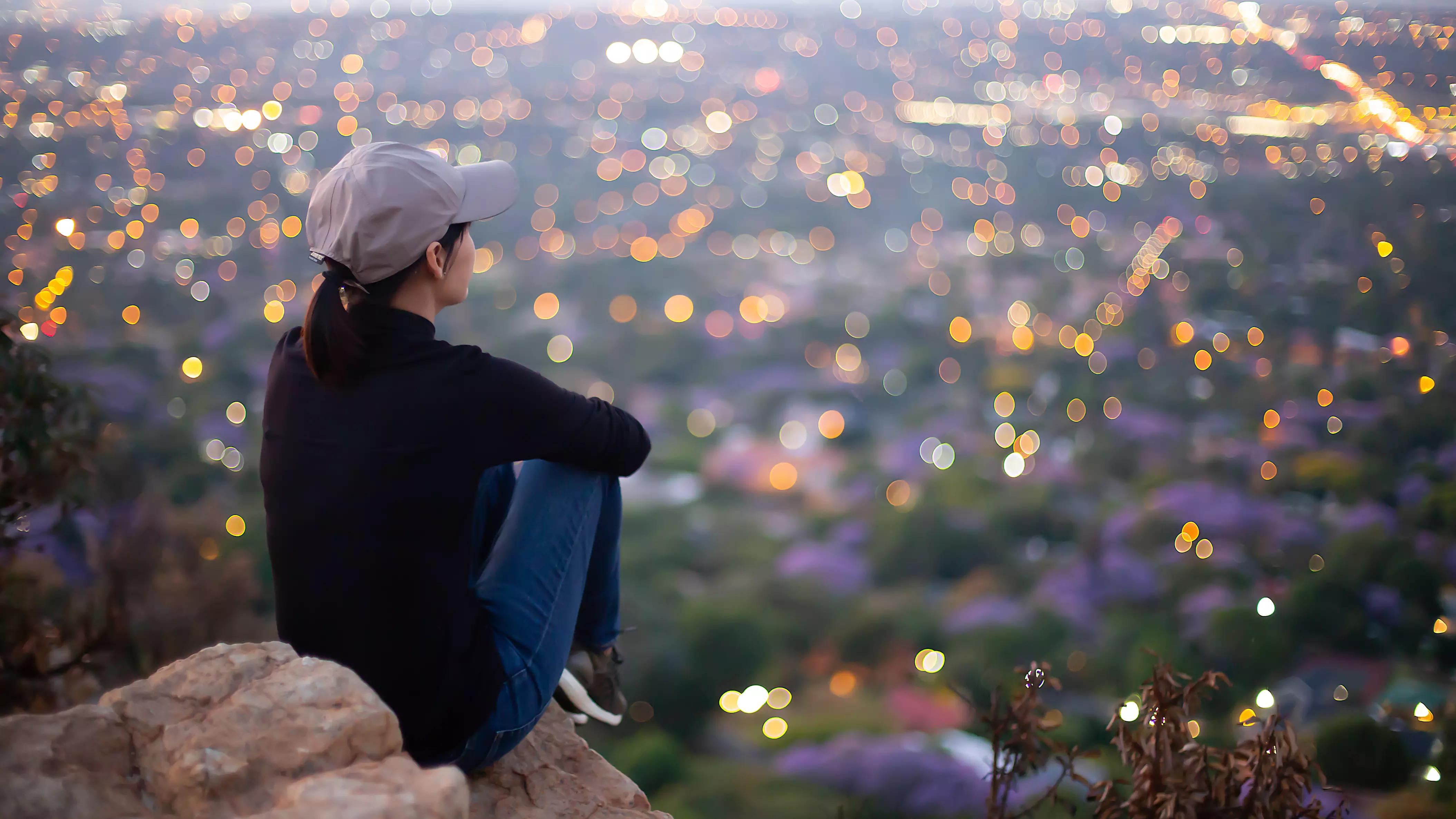 Woman sitting on a rock looking out at the city