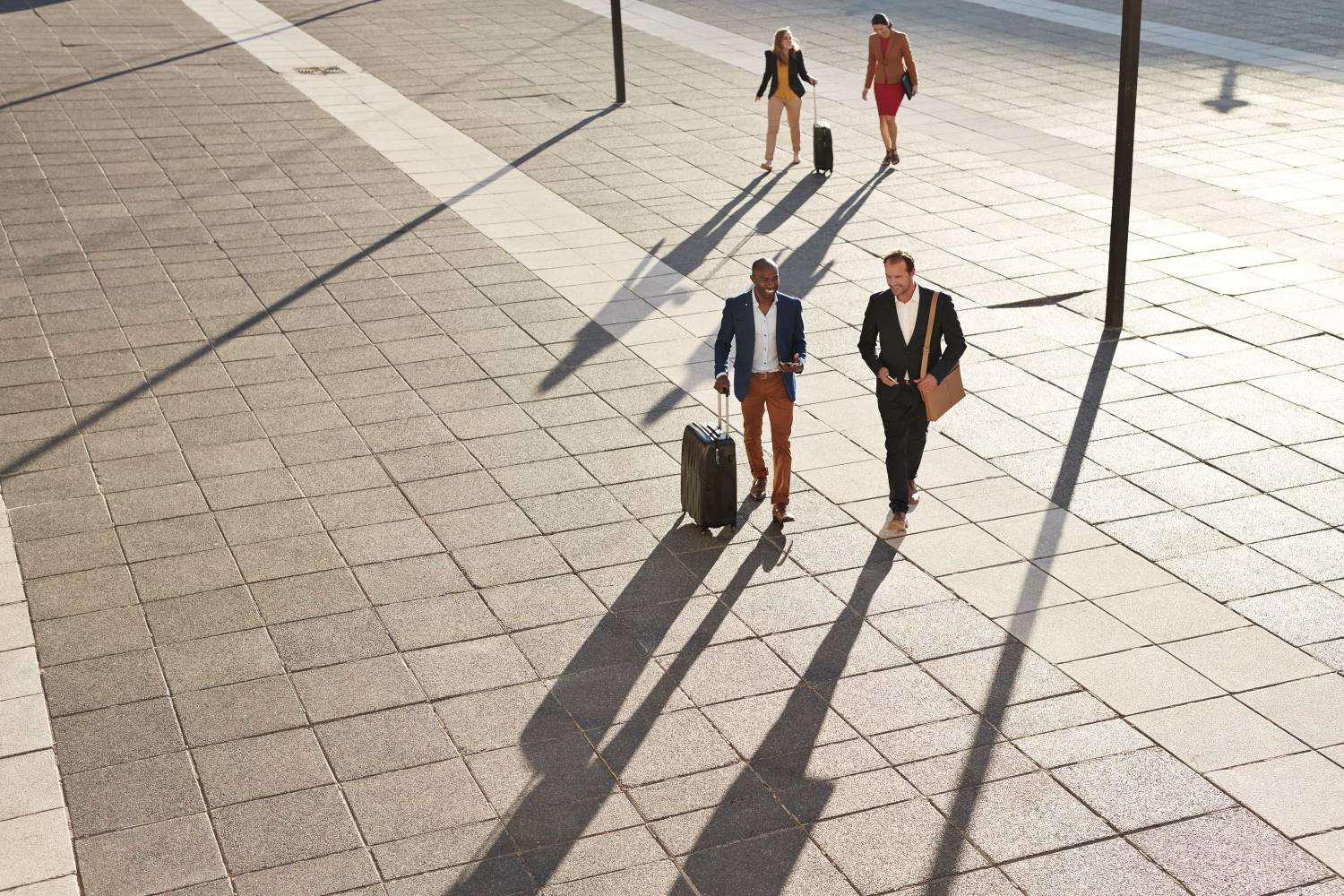 Businesspeople Walking Across Square With Suitcases