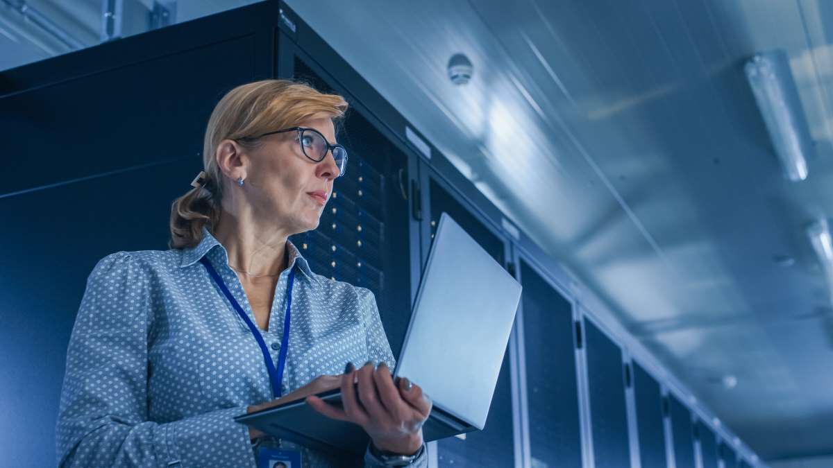 Female IT Tech In Server Room Shutterstock 1363031057 Female IT Technician Running Maintenance Program