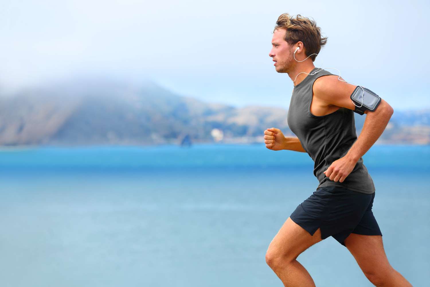 Male runner listening to music with phone armband Male runner listening to music with phone armband